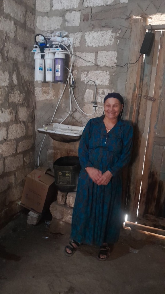 Umm Amir standing beside her new water filter system